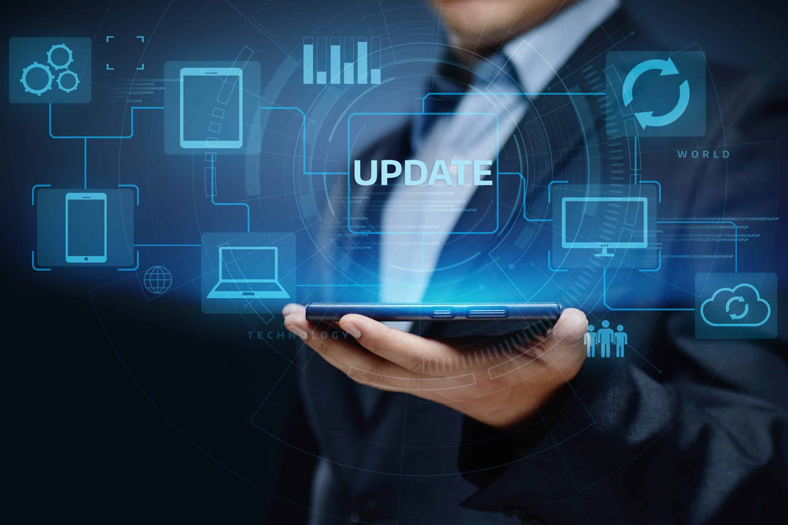 Man in business suit with conceptual graphic of update software around laptops and devices.